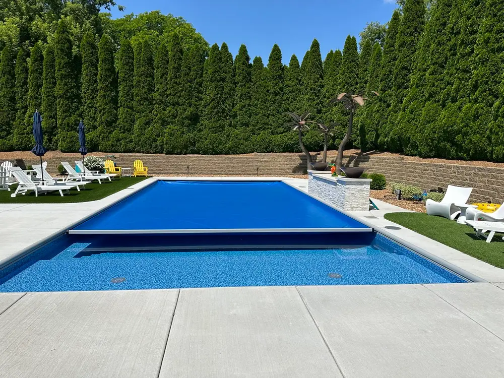 "Beautifully designed pool area featuring a retaining wall, privacy screening trees, synthetic turf, a tranquil waterfall, and palm trees. This setup creates a serene and stylish outdoor oasis perfect for relaxation and enjoyment. #PoolArea #RetainingWall #PrivacyTrees #SyntheticTurf #Waterfall #PalmTrees"