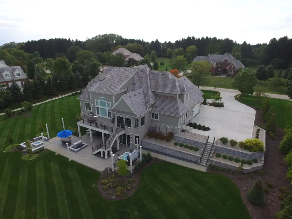 "Transformative outdoor space in New Berlin, WI, featuring a basement-level patio that connects to the upper-level driveway. Highlights include elegant retaining walls, stone steps, and a stylish paver patio, blending functionality with aesthetic appeal. #NewBerlinWI #OutdoorPatio #RetainingWalls #StoneSteps #PaverPatio"