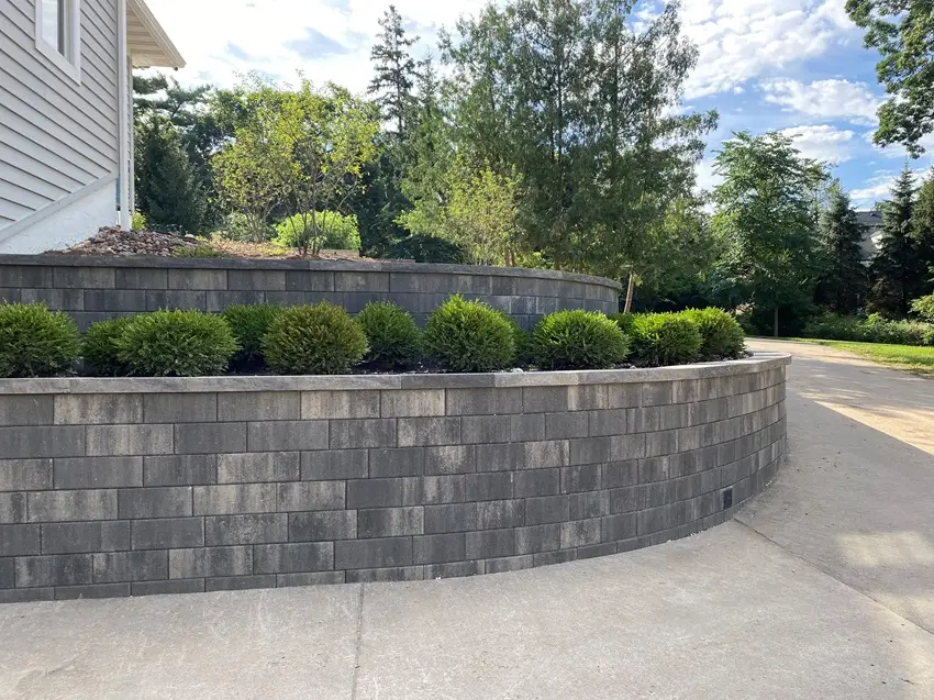 "Stunning dual-level retaining walls complemented by lush shrub plantings. This design adds depth and beauty to your landscape, combining functionality with vibrant greenery. #RetainingWalls #Landscaping #ShrubPlantings #OutdoorDesign"