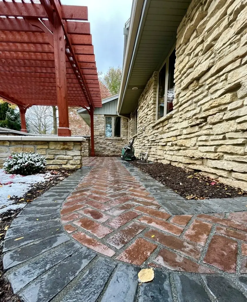 "Charming paver patio leading to a newly designed outdoor living area featuring a bar, grille, griddle, seat walls, and breakfast bar tops. This inviting setup is perfect for both relaxing and entertaining in style. #PaverPatio #OutdoorLiving #Bar #Grille #SeatWalls #BreakfastBar"