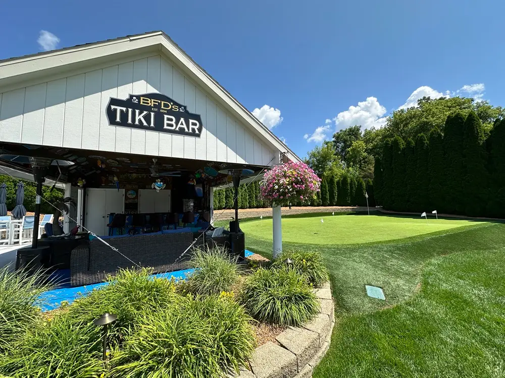 "Transform your outdoor living space with a vibrant tiki bar, sleek retaining walls, and a fun putting green. This dynamic setup combines relaxation, style, and recreational fun for a perfect backyard retreat. #OutdoorLiving #TikiBar #RetainingWalls #PuttingGreen #BackyardDesign"