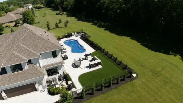 "Inviting outdoor kitchen and paver patio, complete with pet-friendly turf, a fenced-in yard, and privacy trees. This thoughtfully designed space combines comfort and functionality, perfect for both pets and family gatherings. #OutdoorKitchen #PaverPatio #PetTurf #FencedYard #PrivacyTrees"