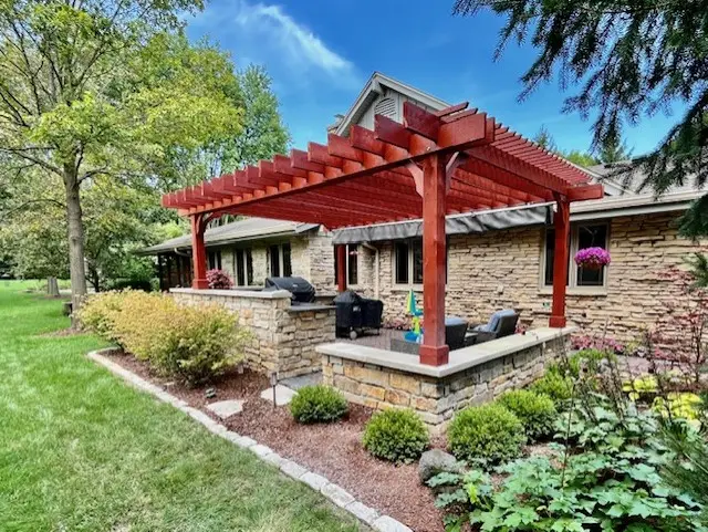 "Seamless outdoor kitchen designed to match the stone of your home, featuring a pergola for shade, dual grille and griddle setup, and a stylish paver patio. Perfect for cooking and entertaining in a cohesive, elegant space. #OutdoorKitchen #StoneDesign #Pergola #DualGrille #PaverPatio"