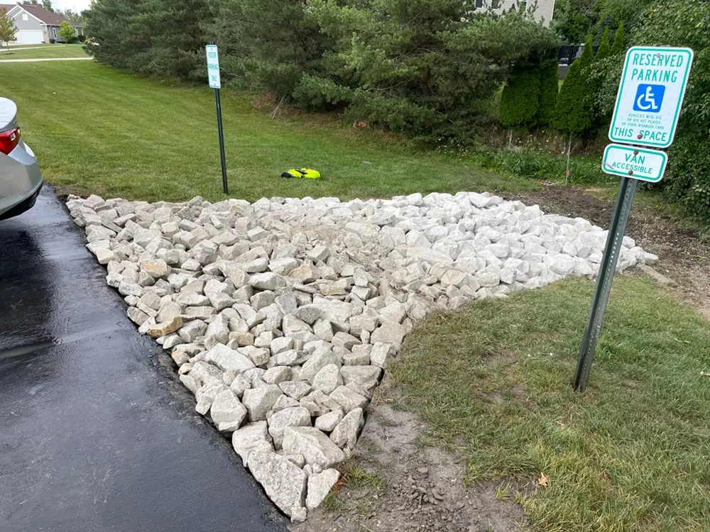 Rip Rap drainage system in New Berlin, WI, featuring large stones placed to control water flow and prevent erosion. The installation stabilizes soil, manages runoff, and offers both durability and an attractive natural look.