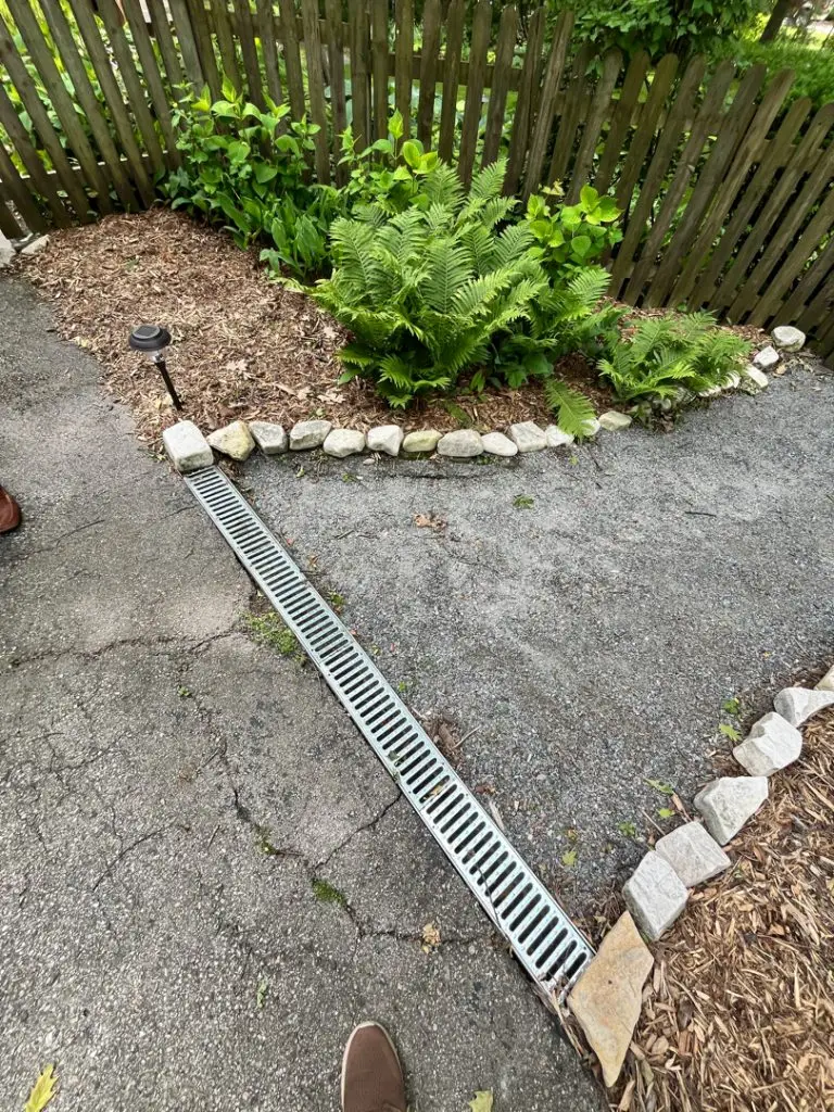 This image highlights a surface driveway drain installation in Brookfield, WI. The drain is designed to efficiently manage water runoff from the driveway, preventing pooling and potential damage. The system seamlessly integrates with the existing surface, ensuring effective drainage and maintaining the functionality and aesthetics of the driveway.