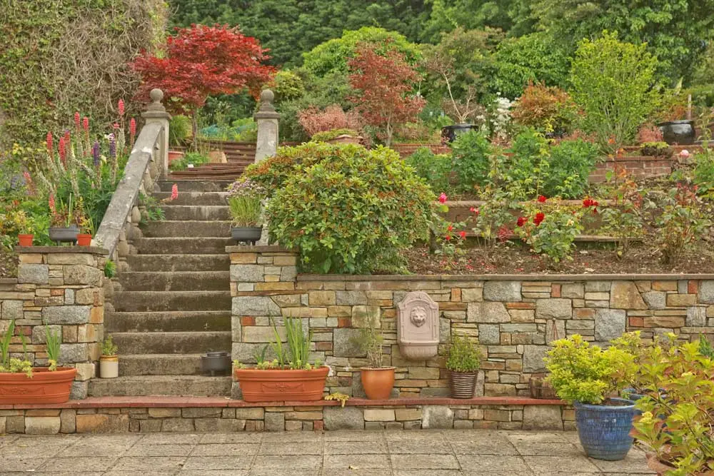 "Charming Victorian garden in River Hills, Wisconsin, featuring a beautifully crafted retaining wall and elegant steps. This classic design adds timeless appeal and structure to the garden, enhancing its picturesque setting. #RiverHillsWI #VictorianGarden #RetainingWall #GardenSteps"